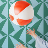 Parasol wallpaper is designed with overlapping shapes of multicolored beach umbrellas. Highly durable, fade resistant, and made in the USA. This wallpaper has a green print on a light blue background and is designed in collaboration with The Aesthetics of Joy.
