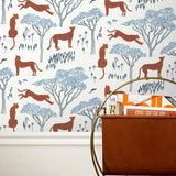 Our Serengeti wallpaper features orange cheetahs and navy birds scattered among blue acacia trees on a white background, reflecting the powerful beauty of the vast plains. Designed by Julia Rothman and made in the USA.