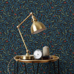 Olive Grove (Ebony) featuring a leafy vine motif in shades of green and blue with deep red accents on a black background | Schoolhouse x Hygge & West Wallpaper Collection