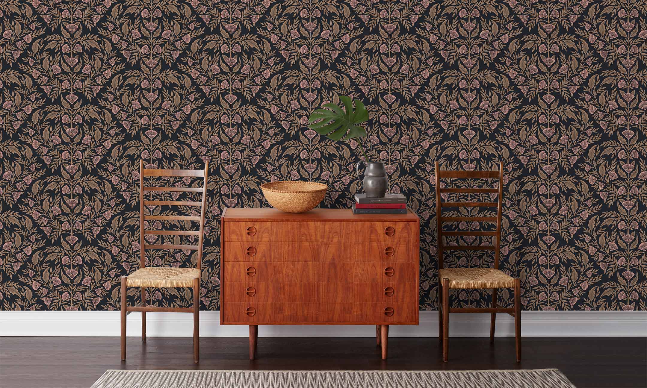 Symmetry wallpaper is a stylized floral wallpaper and designed in linocut style by Katharine Watson for Hygge & West | Metallic gold and pink flowers on a soft black wallpaper background.